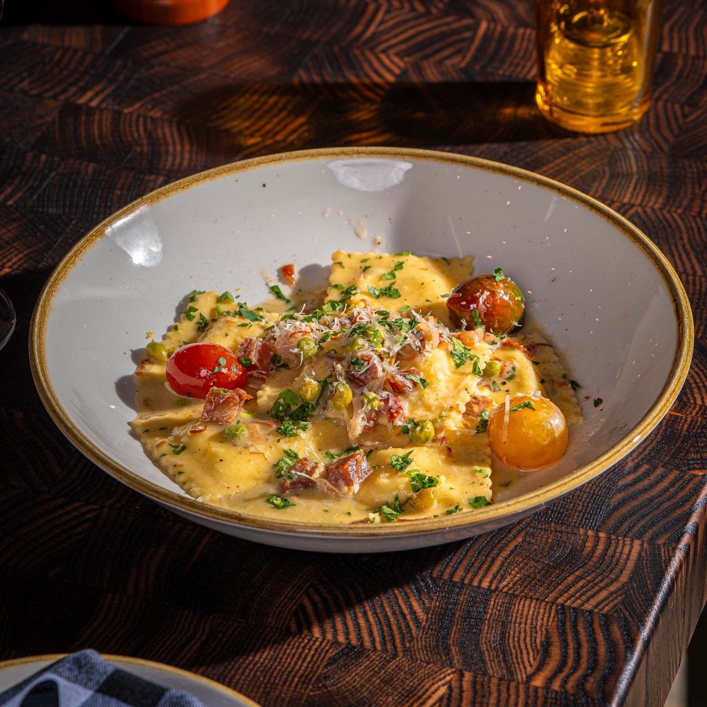 A pasta dish sits on a wood table.